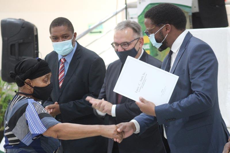 One of the beneficiaries of the pilot project receiving her title deeds during the handover ceremony.