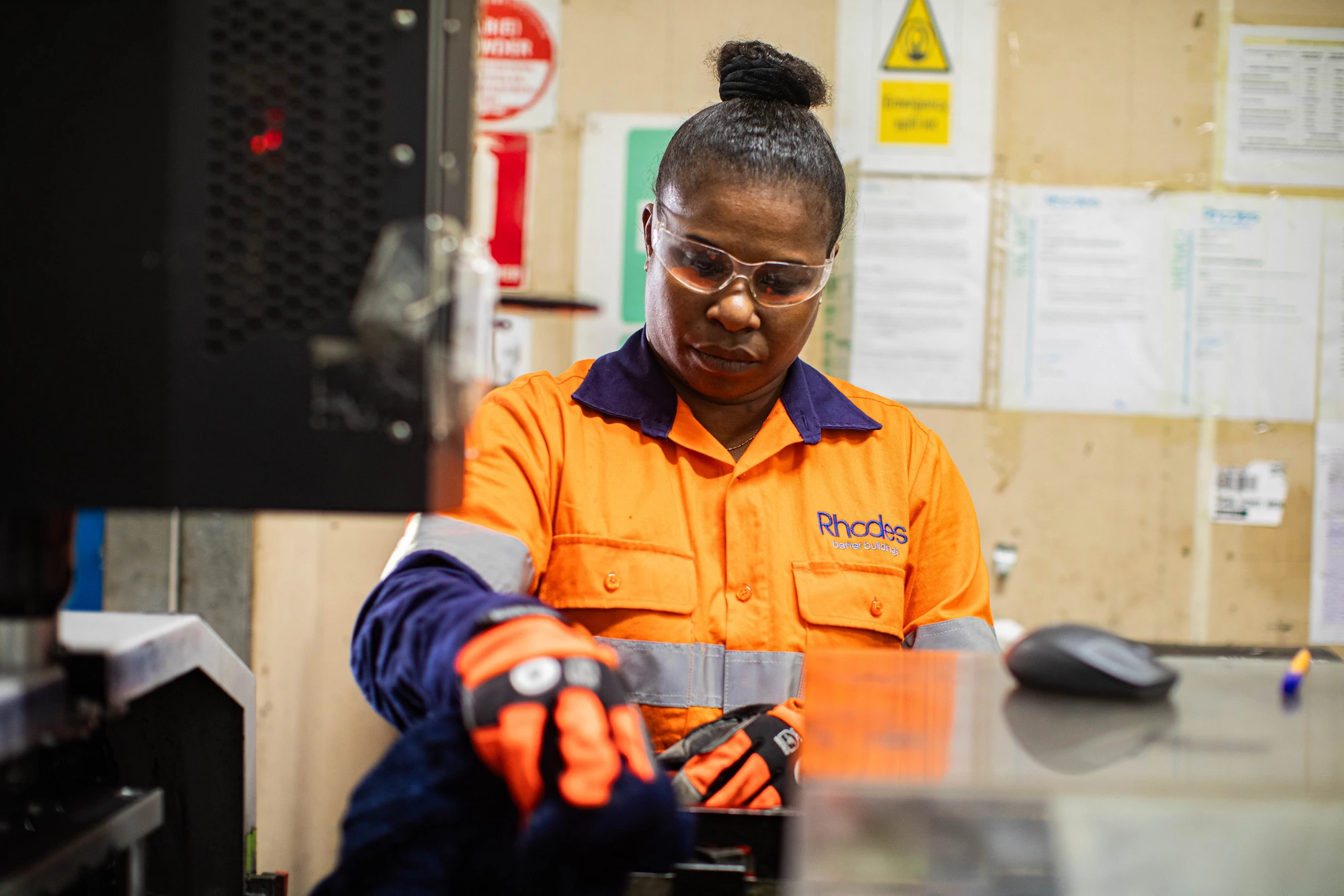Factory Manager Jacobeth Misiel, in safety clothing, operates a machine on site at Rhodes PNG Ltd.