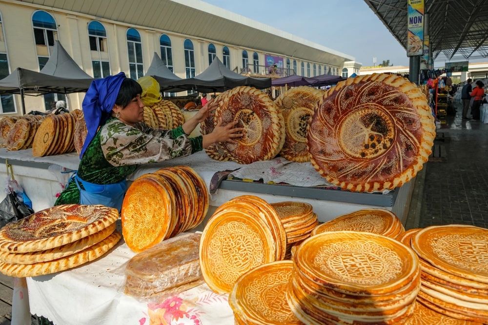 Fergana, Uzbekistan - October 18, 2023: A bread seller at the City Market in Fergana, Uzbekistan.